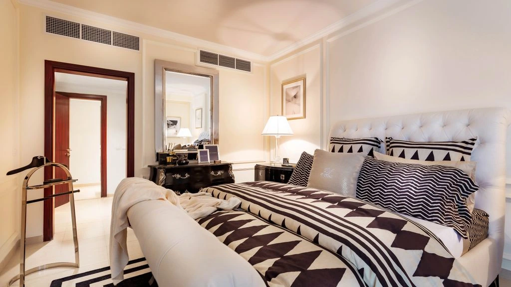 Vue intérieure de la suite Oliviers, lit en fer forgé et lin brut.
